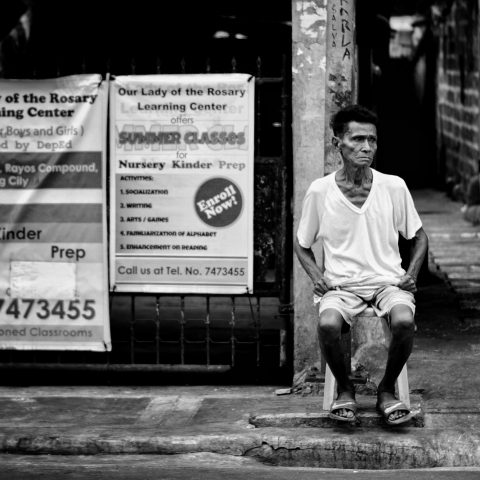 Old man, sitting intently by the street.