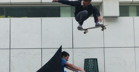 Boy jumping above his friend on a skateboard