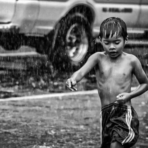 Holding onto his loose shorts, while bathing in the rain.