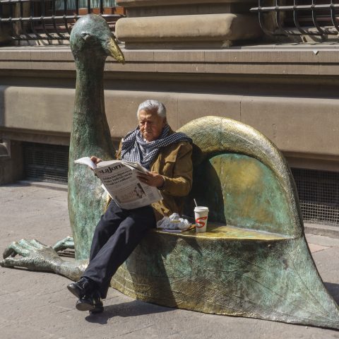 Reading a newspaper seating a bench
